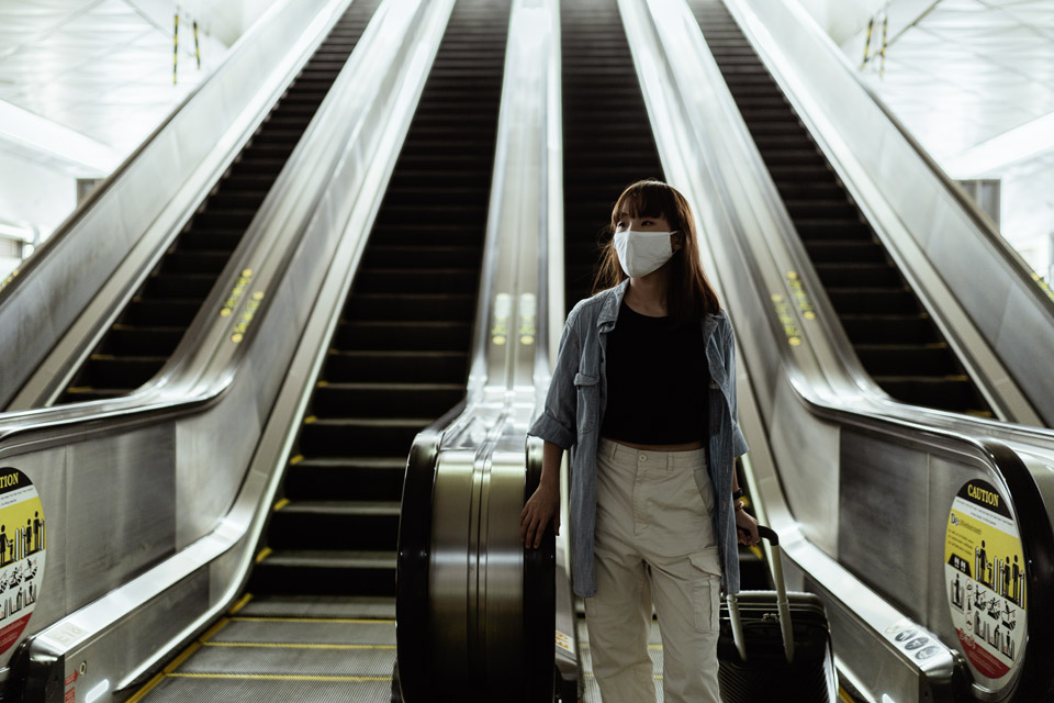 woman with a face mask going down an escalator 4429654 - FACES.ch